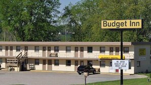A motel named Budget Inn with a row of rooms, a parking lot, and a signboard.