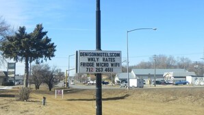 A sign for Budget Inn with a smaller sign below advertising weekly rates and a contact number.