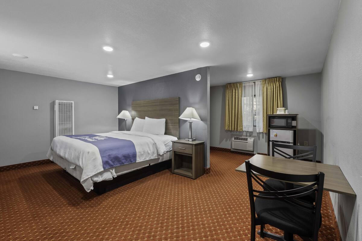 A hotel room with a bed, bedside tables, a desk, and a chair.