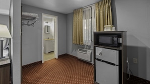 A compact hotel room with a kitchenette, a microwave, a refrigerator, a heater, and a door leading to a bathroom. - Budget Lodge Ruidoso (Ruidoso)