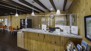 A reception area with a wooden interior, a marble counter, and a clock on the wall. - Budget Lodge Ruidoso (Ruidoso)
