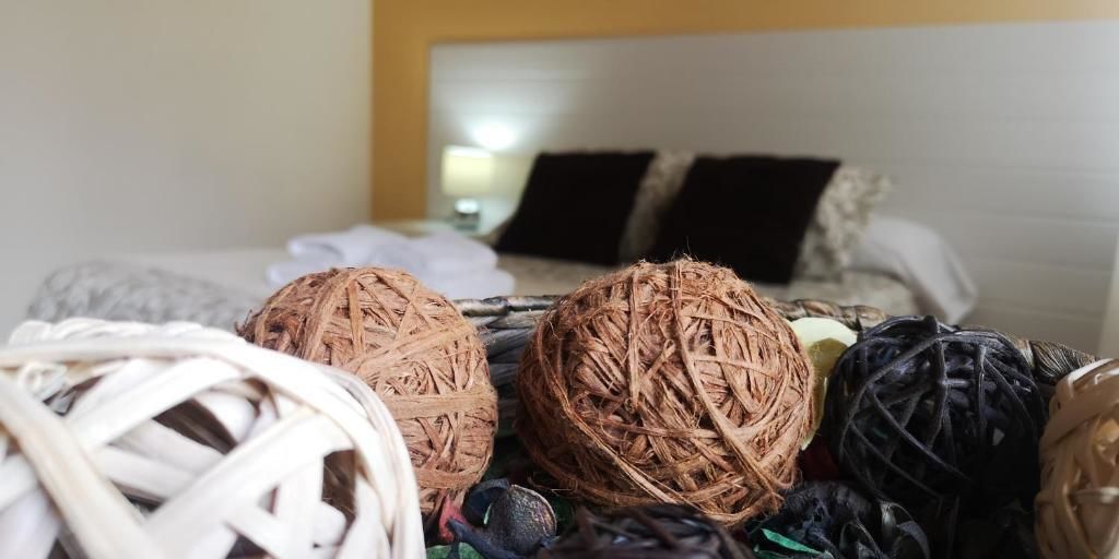 Una cama con cabecera blanca y almohadas negras, rodeada de cestas tejidas.