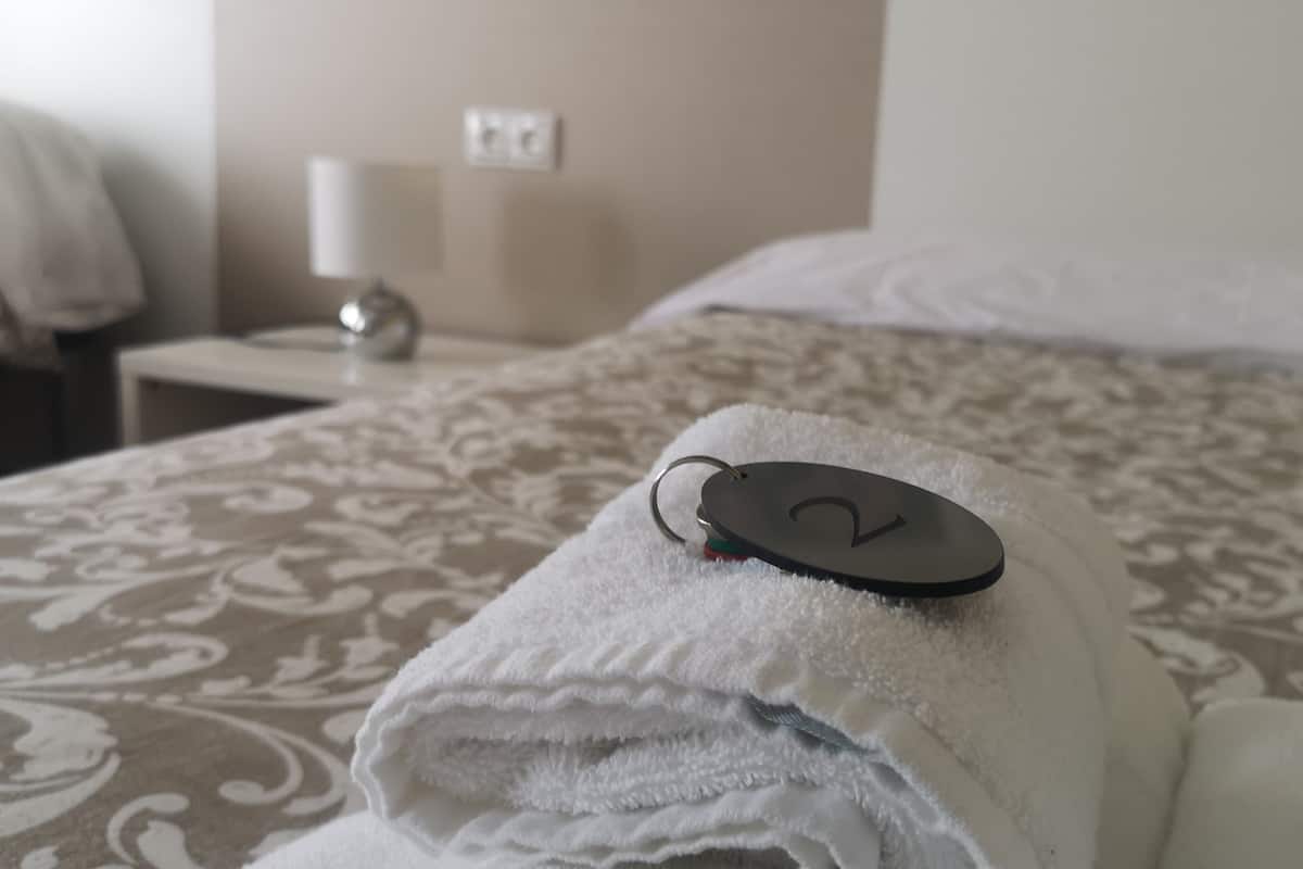 A neatly made bed with a folded towel and a keychain on it.