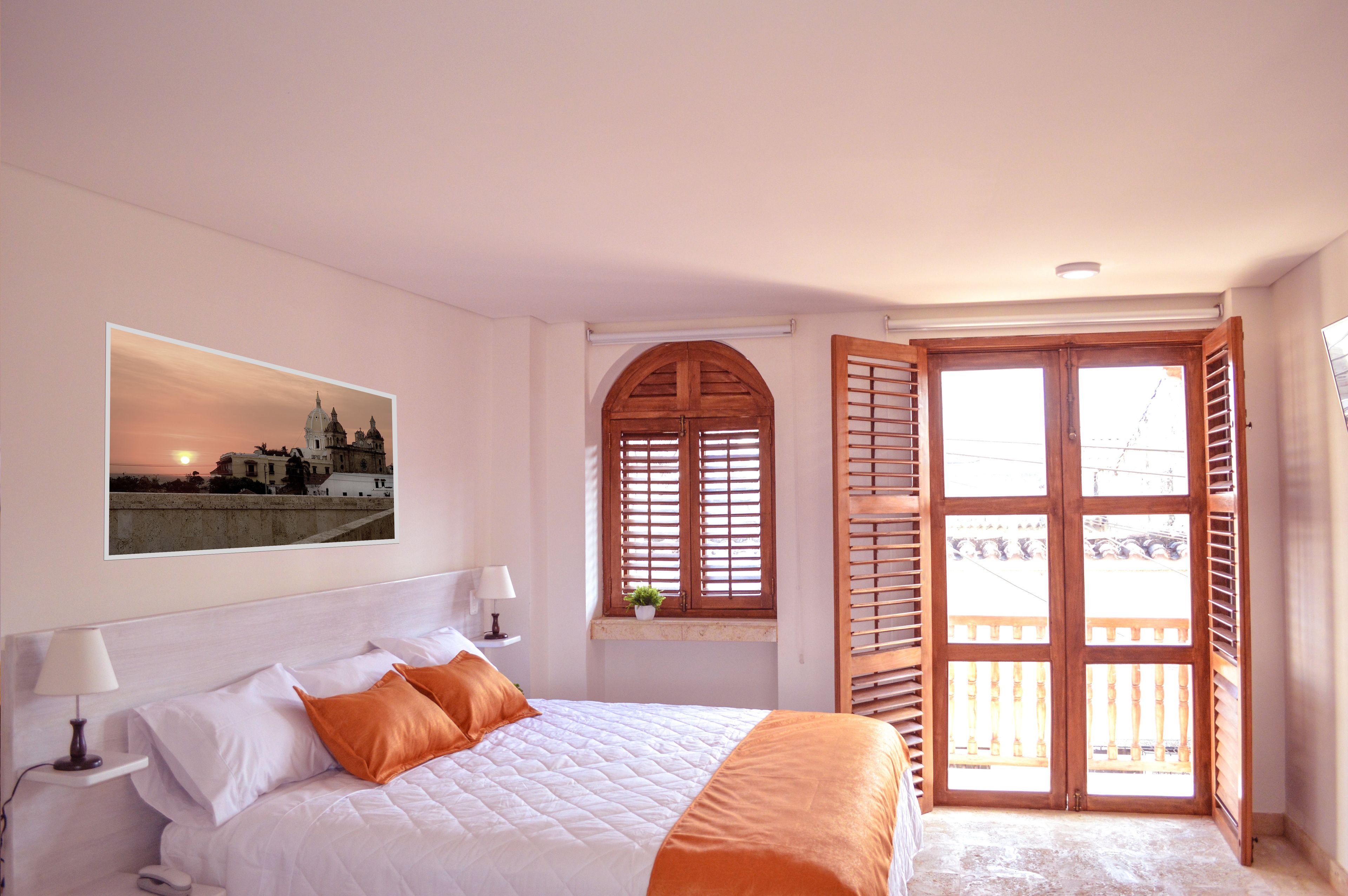 Een hotelkamer met een bed, een raam met luiken, uitzicht op een gebouw en een schilderij aan de muur.
