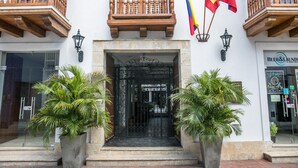A building entrance with a wrought iron gate, wooden balconies, and flags. - Hotel Boutique La Artillería (Cartagena)