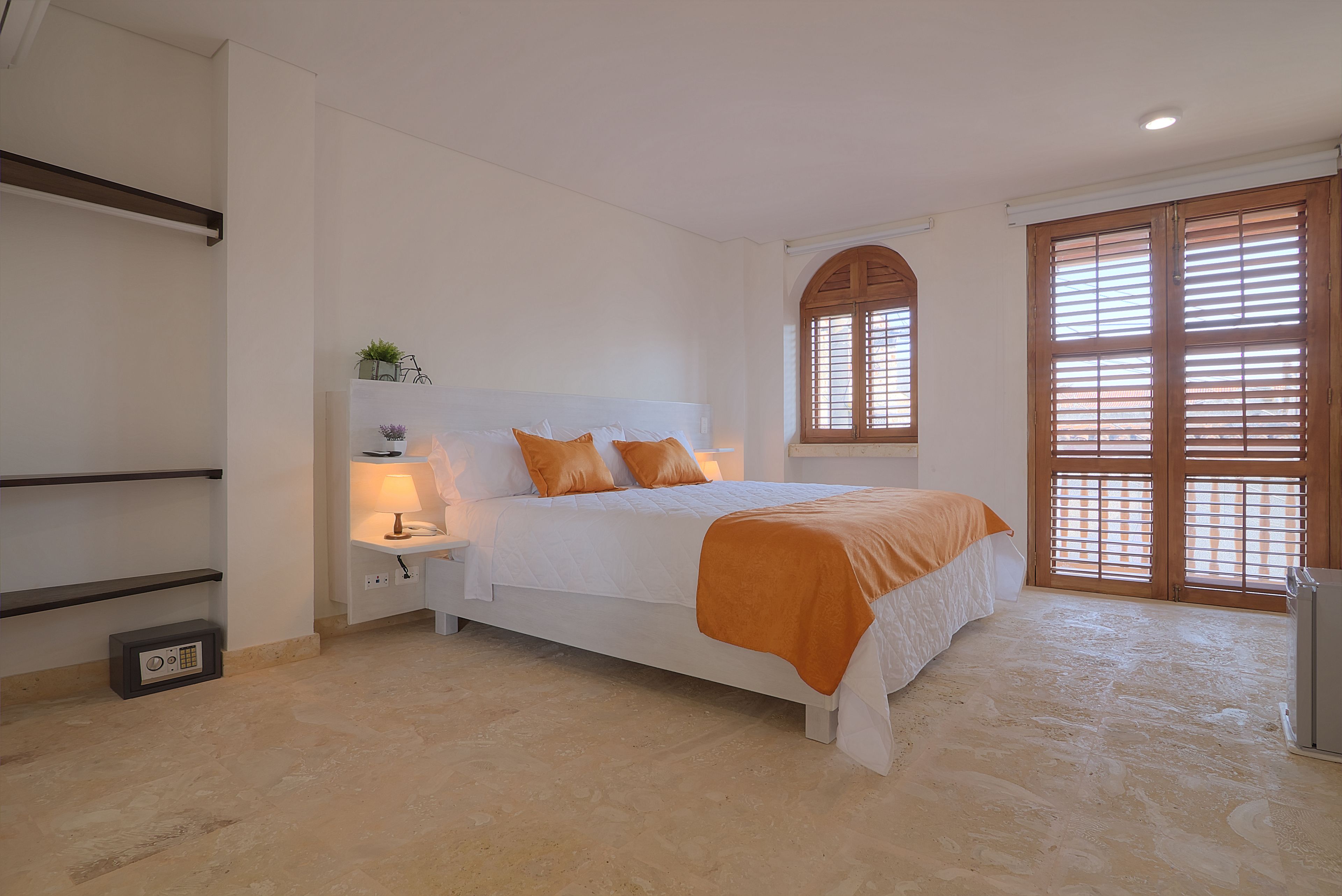 Une chambre à coucher avec un lit, une table de chevet, une lampe et une fenêtre avec des stores.