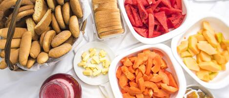 A variety of food items including bread, watermelon, and fruits on a white surface.