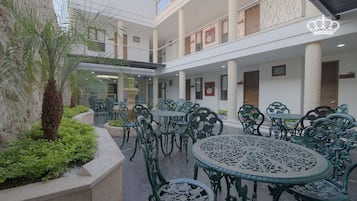 A courtyard with outdoor seating, palm trees, and a decorative fountain.