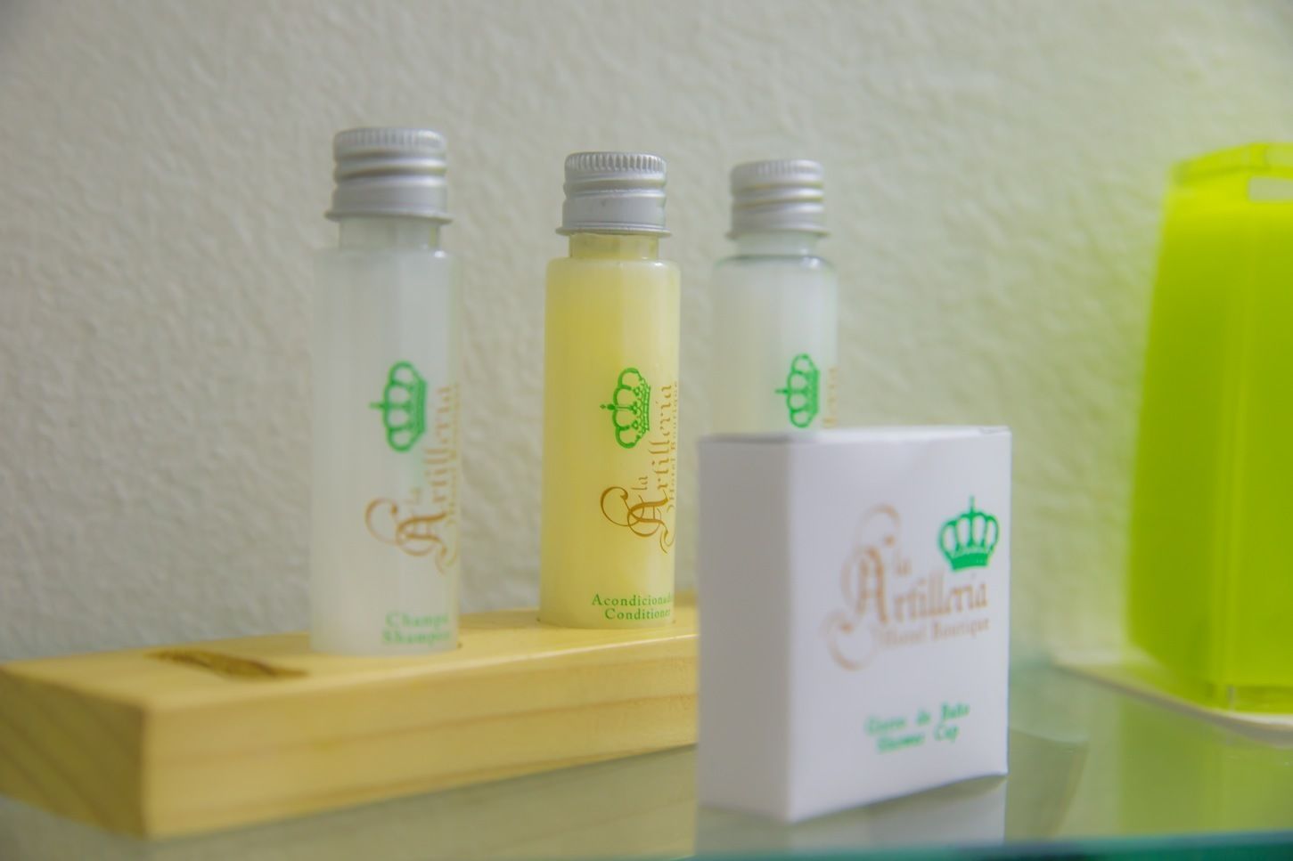 Tres botellas de productos para el cabello y una caja sobre un estante de madera frente a una pared con textura.