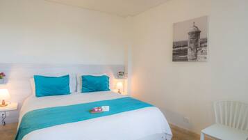 A bedroom with a bed, a nightstand, a chair, and a wall-mounted picture.