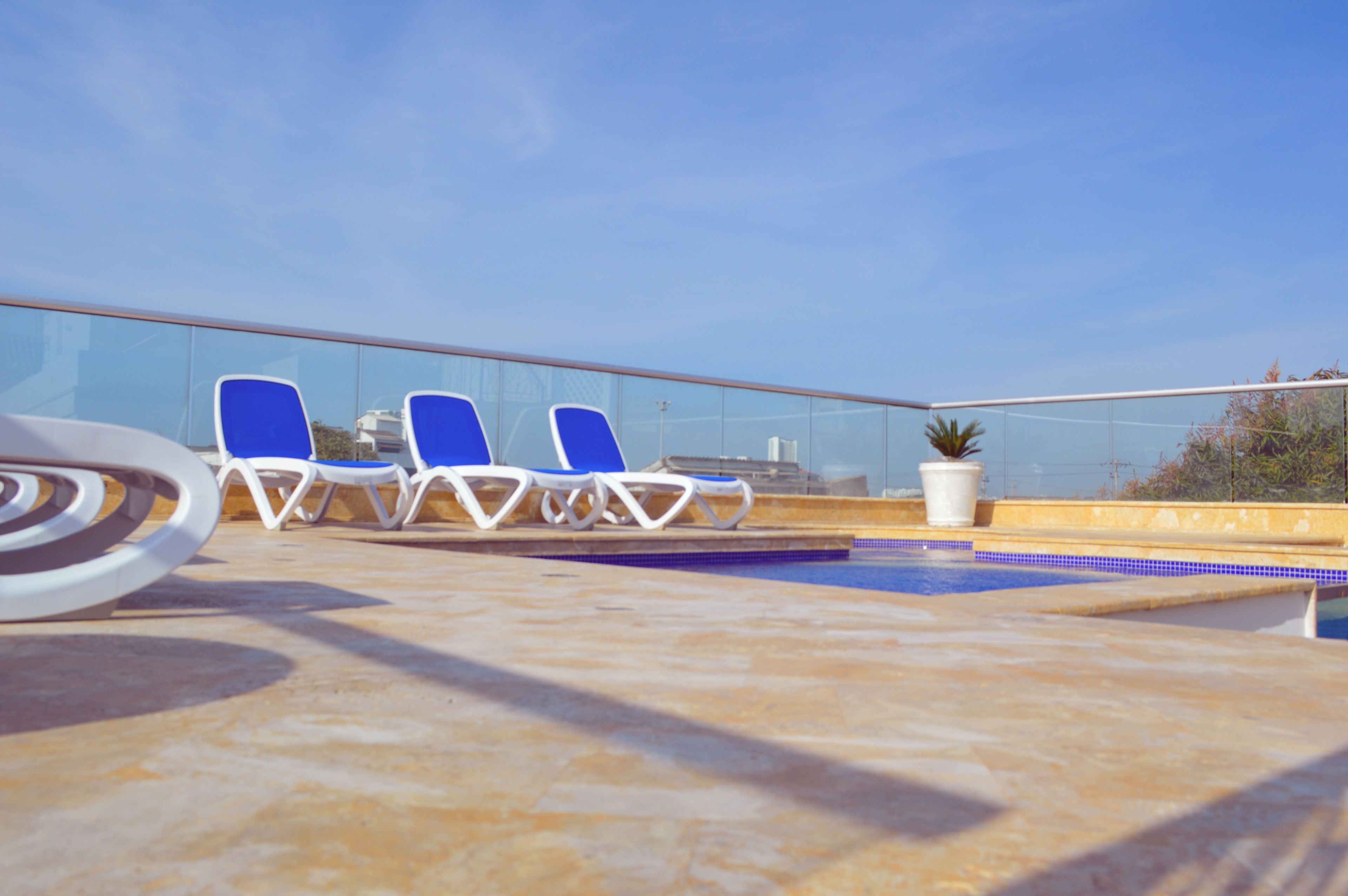 Un espace piscine aménagé sur le toit, avec des chaises longues bleues et une petite plante en pot.