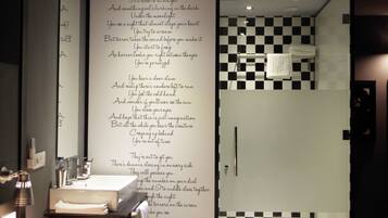 A bathroom with a black and white checkered wall, a sink, and a mirror.