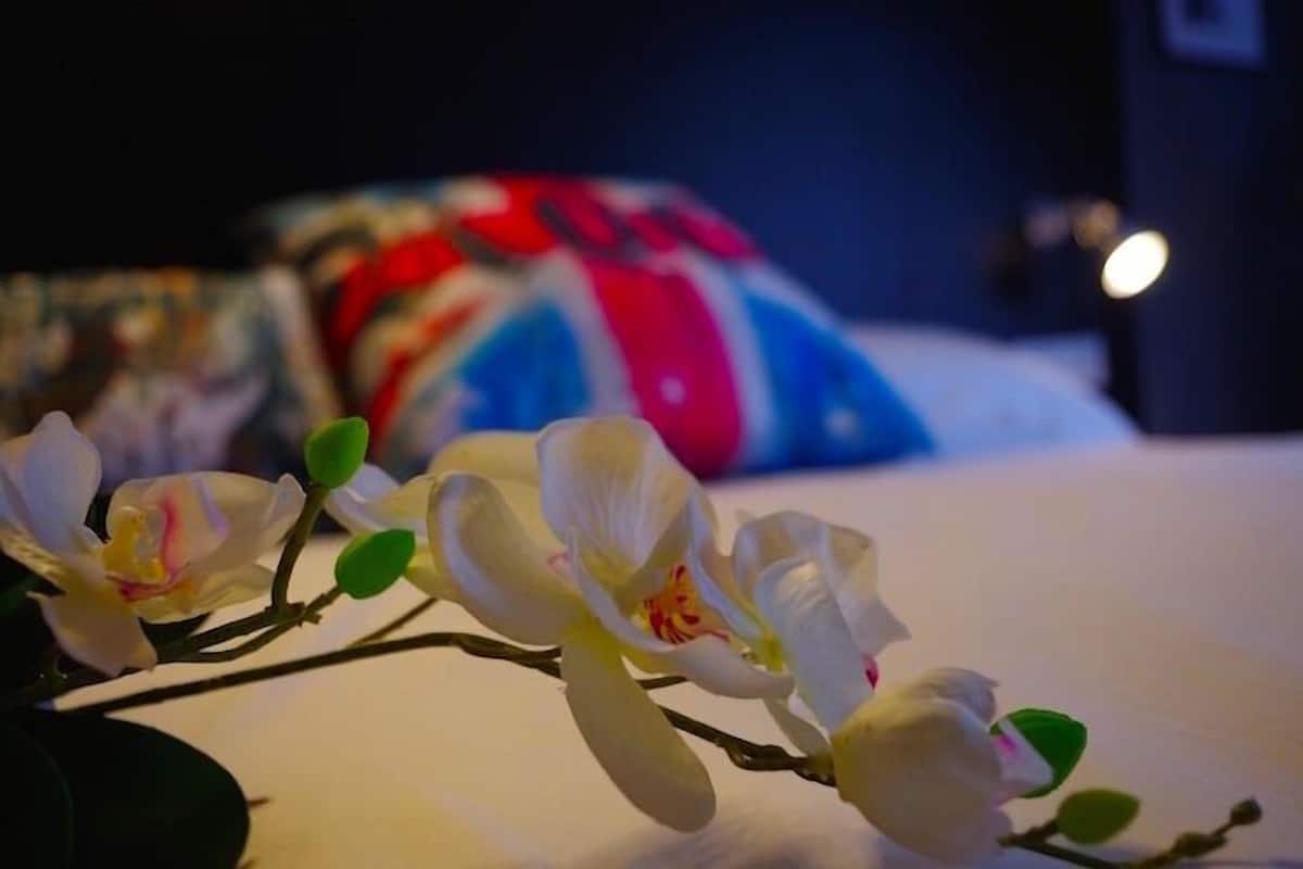 Una cama con ropa blanca y un arreglo floral en primer plano.