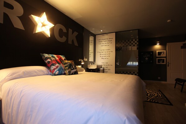A bedroom with a large bed, a star-shaped light fixture, and a wall with the word "ROCK" and a poster with lyrics. - HOTEL Rock Star (Taboadela)