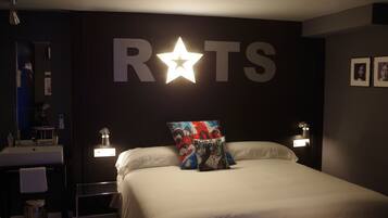 Habitación de hotel con cama, mesita de noche, una estrella en la pared y un cartel grande que dice 'ROTS'.