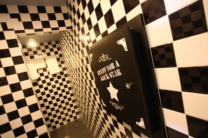 A hallway with black and white checkered walls and a door with a star emblem and text. - HOTEL Rock Star (Taboadela)