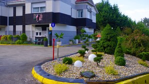 Un hotel de diseño moderno, con una estructura de dos pisos, entrada visible y un jardín ajardinado con diversas plantas y un camino de grava.