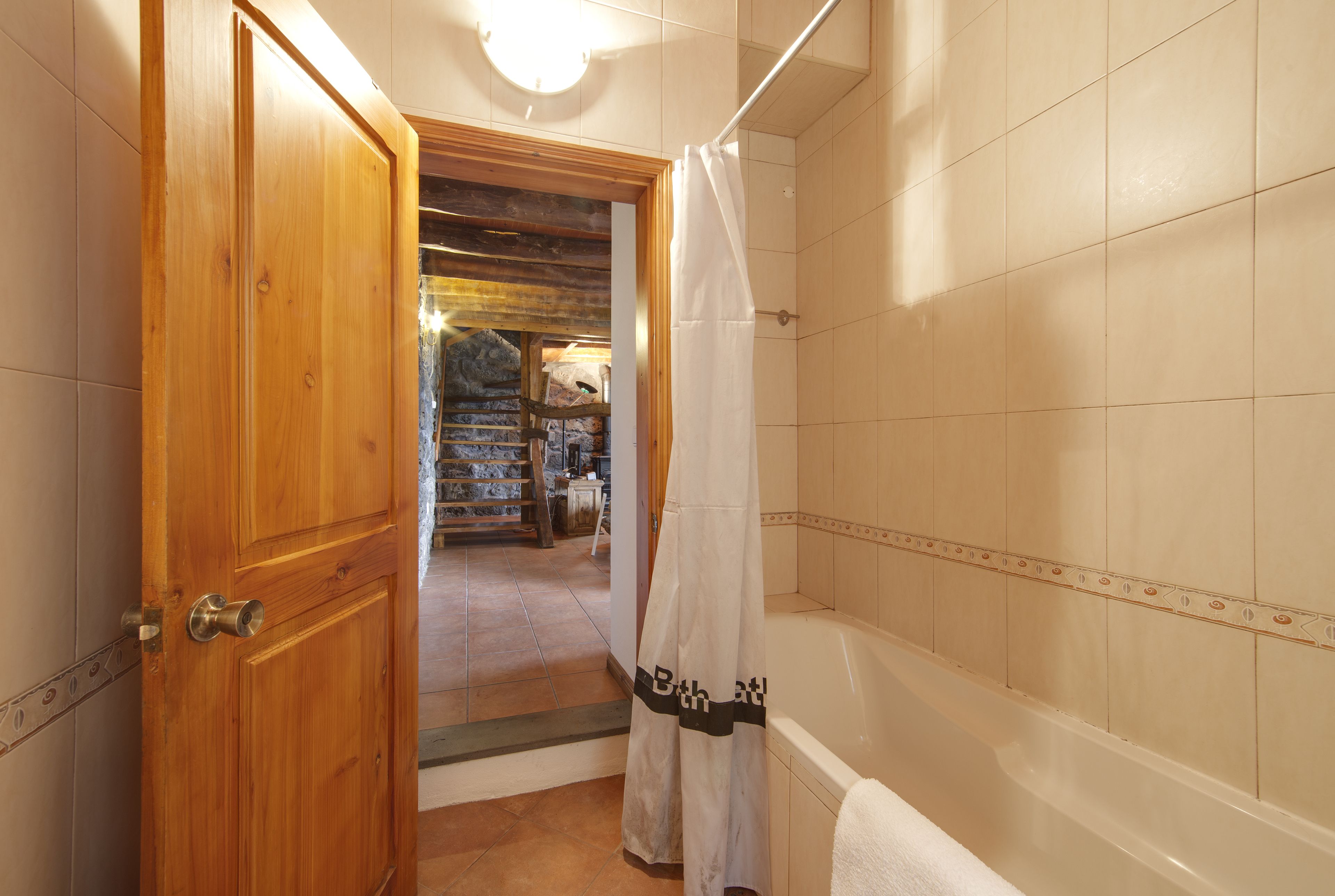 Ein Badezimmer mit Holztür, Duschvorhang und Badewanne.