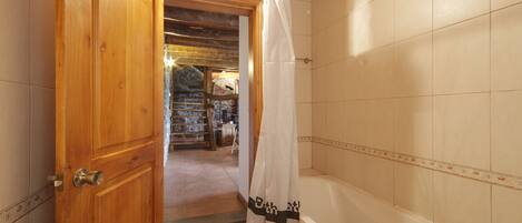Ein Badezimmer mit Holztür, Duschvorhang und Badewanne.