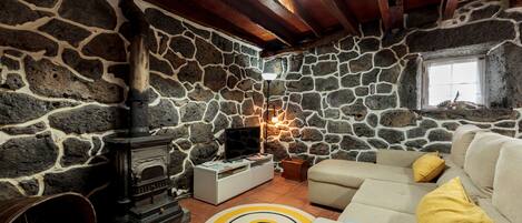 A cozy living room with a stone wall, a fireplace, a sofa, and a circular rug.