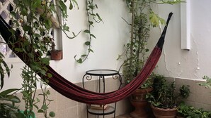 Een terras met een hangmat, plantenpotten en een klein tafeltje.