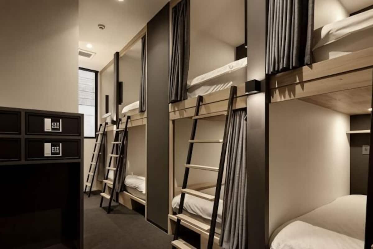 A bunk bed room with a ladder, a desk, and a wardrobe.