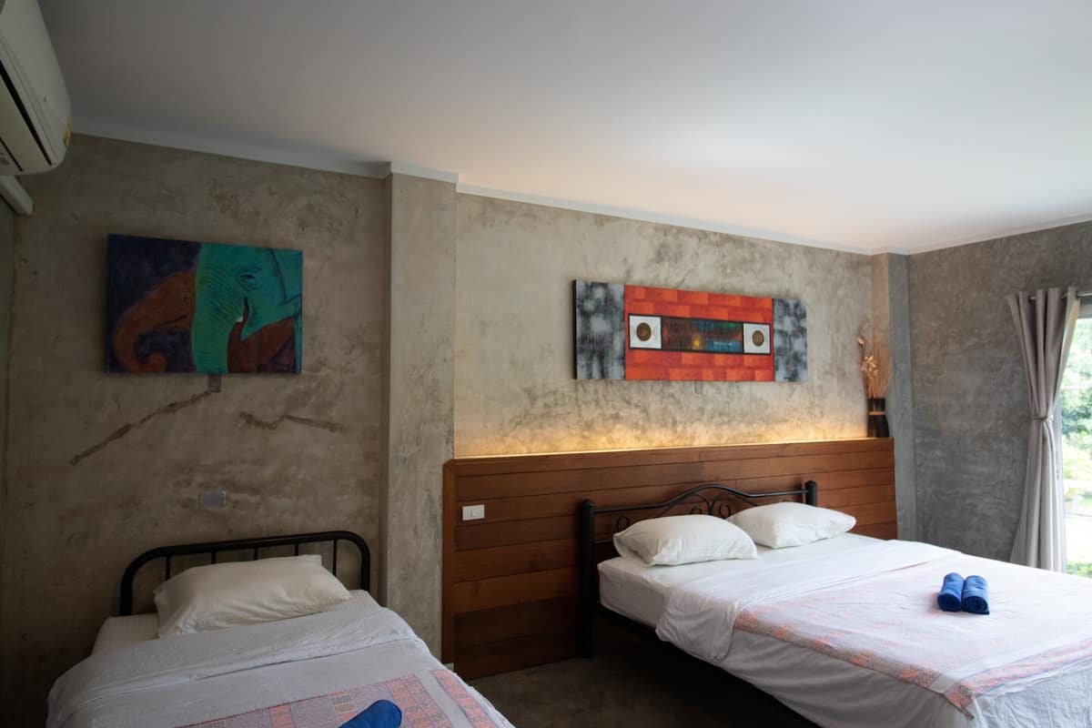 A bedroom with two single beds, a wooden headboard, and artwork on the walls.