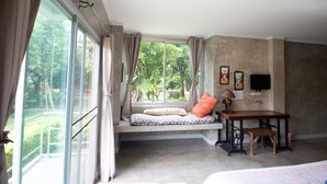 A bedroom with a built-in window seat, a small table, and a television mounted on the wall. - GongKaew HuenKum Hotel (Chiang Mai)