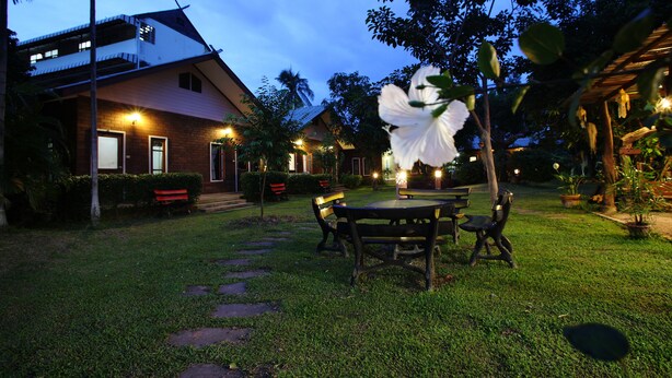 A two-story house with a well-maintained garden, outdoor seating, and a large white flower in the foreground. - GongKaew HuenKum Hotel (Chiang Mai)