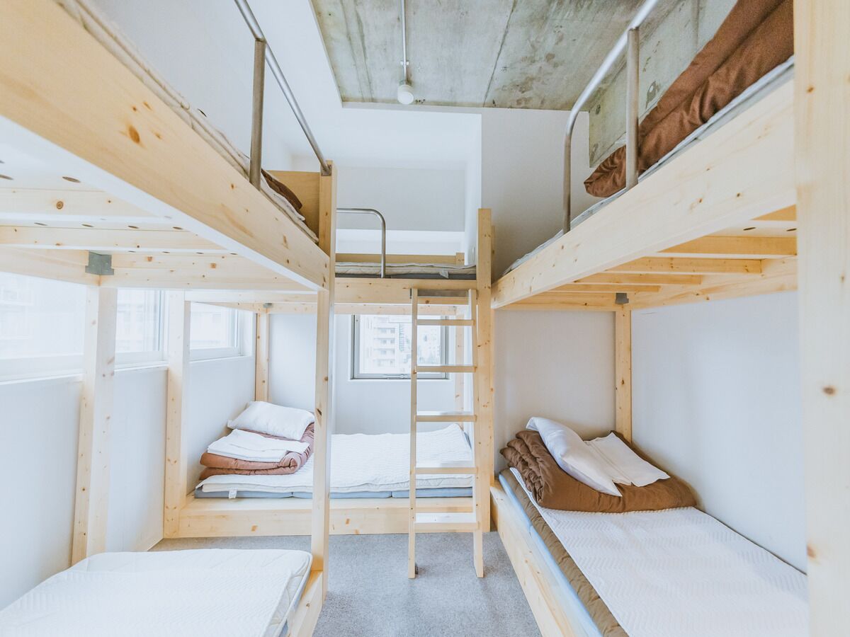 A bunk bed room with a ladder, a window, and a view of the outside.