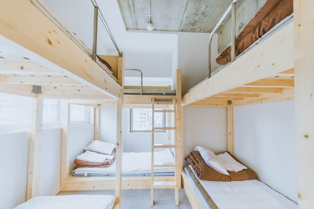 A bunk bed room with a ladder, a window, and a view of the outside.