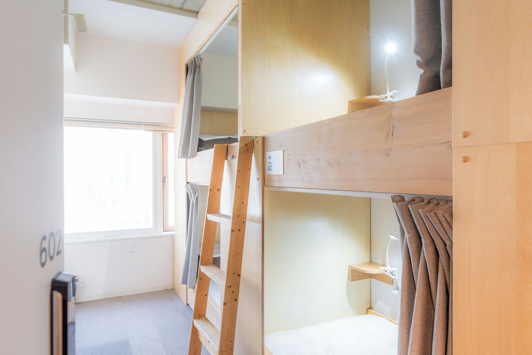 Habitación con literas, una ventana, un escritorio y una lámpara.