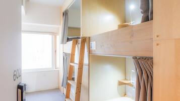 Habitación con literas, una ventana, un escritorio y una lámpara.