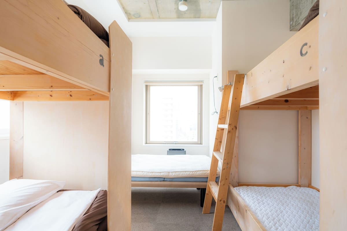 A bunk bed room with a window, a desk, and a chair.