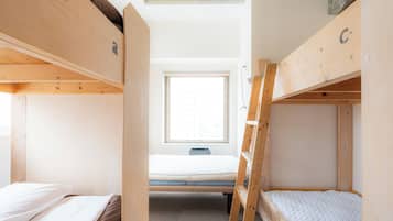 Habitación con literas, un escritorio y una silla, con ventana.