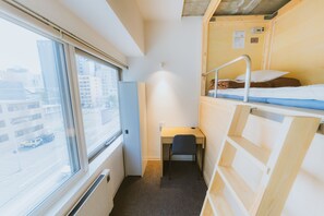 A compact room with a bunk bed, a desk, and a chair. There is a window providing a view of the city. - Grand Hostel LDK Sapporo (Sapporo)