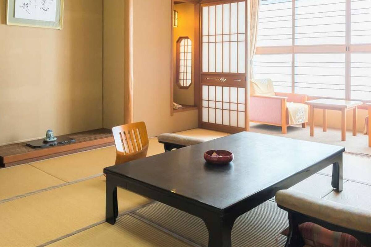 A traditional Japanese room with tatami flooring, a low table, a television, and sliding doors.