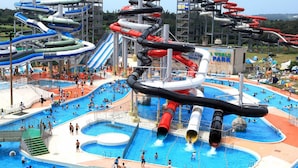 A water park with multiple slides and pools, a sign reading "WORLD PARK", and a large outdoor area with people. - Awara Grand Hotel (Awara)