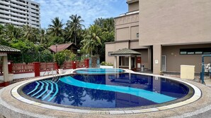 A circular swimming pool with a stone edge, surrounded by a low stone wall. - Puteri Bay Hotel Melaka (Malacca City)