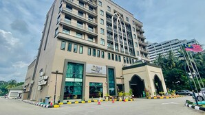 A multi-story hotel with a prominent entrance, air conditioning units, and a flag. - Puteri Bay Hotel Melaka (Malacca City)