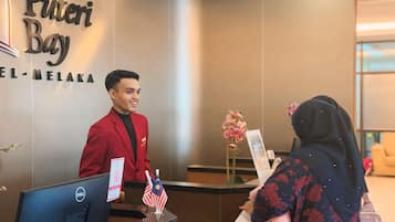 Un mostrador de recepción de hotel con un cartel que dice "Puteri Bay" y "EL-MELAKA".