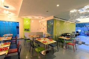 Un restaurante moderno con mesas preparadas para comer, una zona de bar y un techo decorativo.