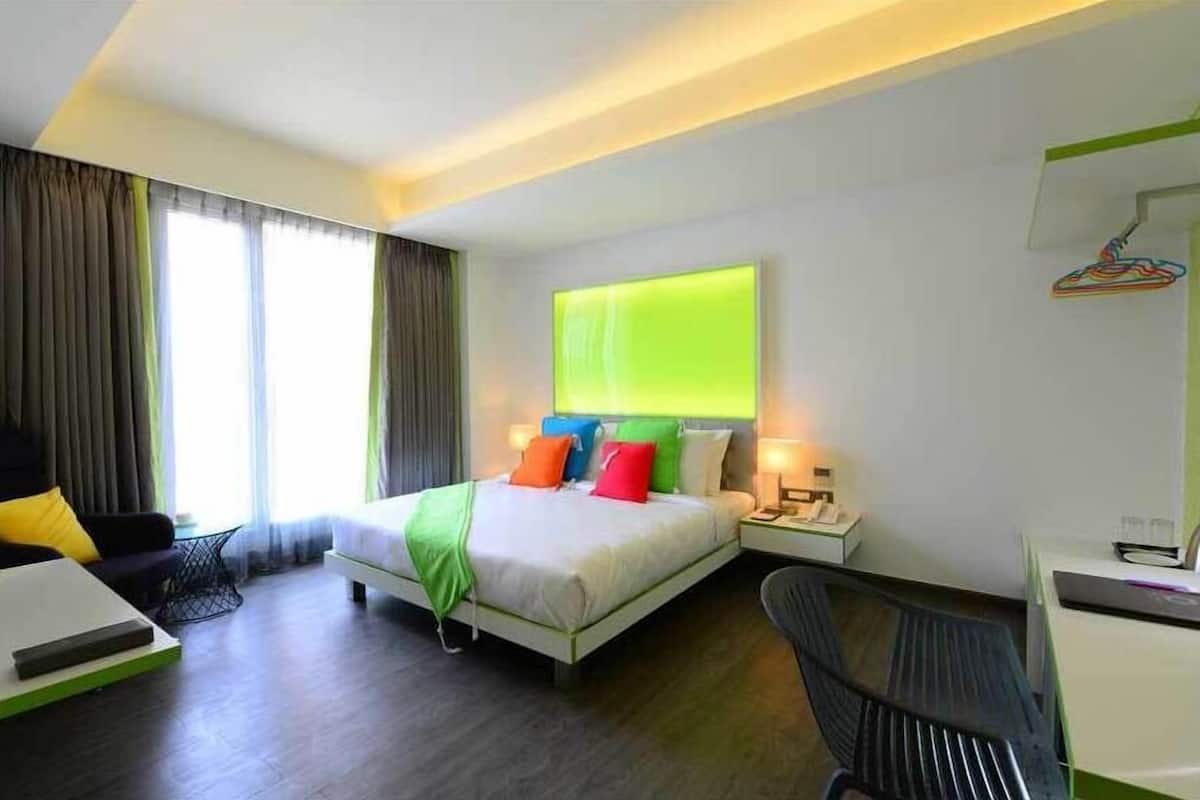Une chambre d’hôtel moderne équipée d’un lit, de tables de chevet, d’un bureau et d’une chaise.