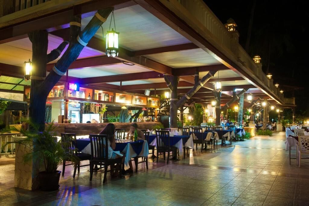 An outdoor dining area with tables and chairs, a bar, and hanging lanterns.
