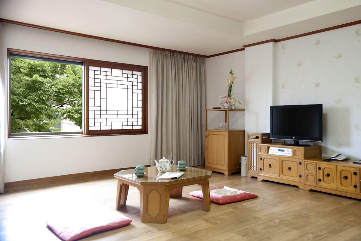 Una sala de estar con un mueble de madera, un televisor y un ventanal con vistas a árboles.