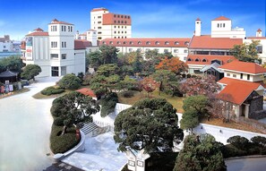 A large building with multiple floors, a red roof, and a courtyard with trees and a fountain.