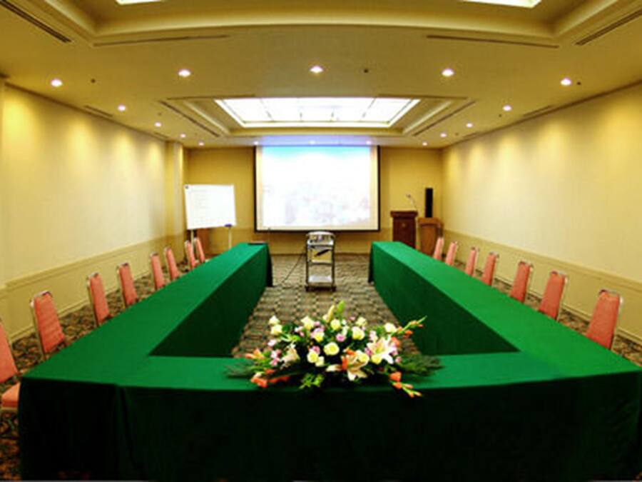 A conference room with a long table, chairs, a projector screen, and a podium.