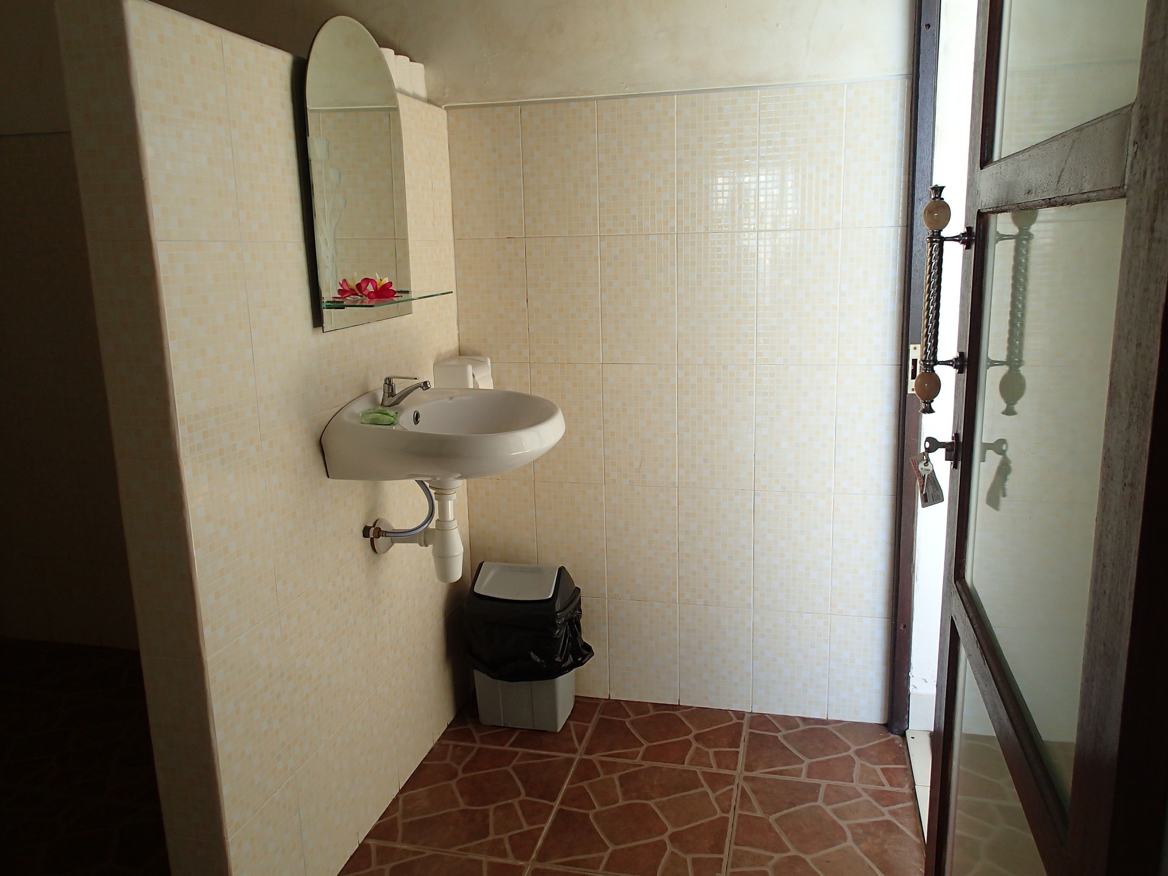 A bathroom with a white sink, a mirror, and a trash bin.