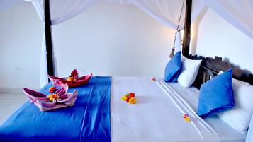 A bed with a canopy, blue bedding, and a floral arrangement.