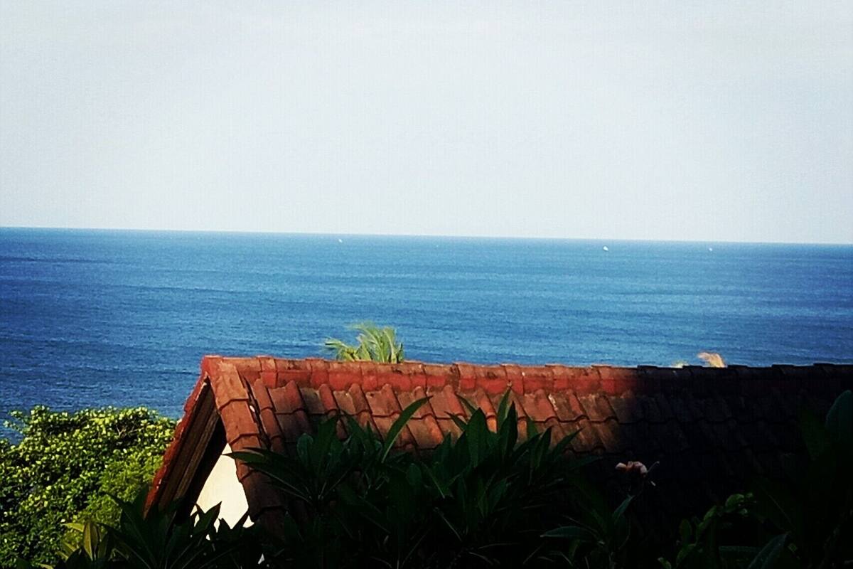 Une vue sur la côte, avec une mer bleue et limpide et un mur de briques au premier plan.
